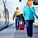 People towing luggage walking down a train platform