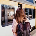 A person wearing a backpack waiting to board a train in a station