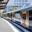 Shiny silver Metro train stopped at a station with an empty patform