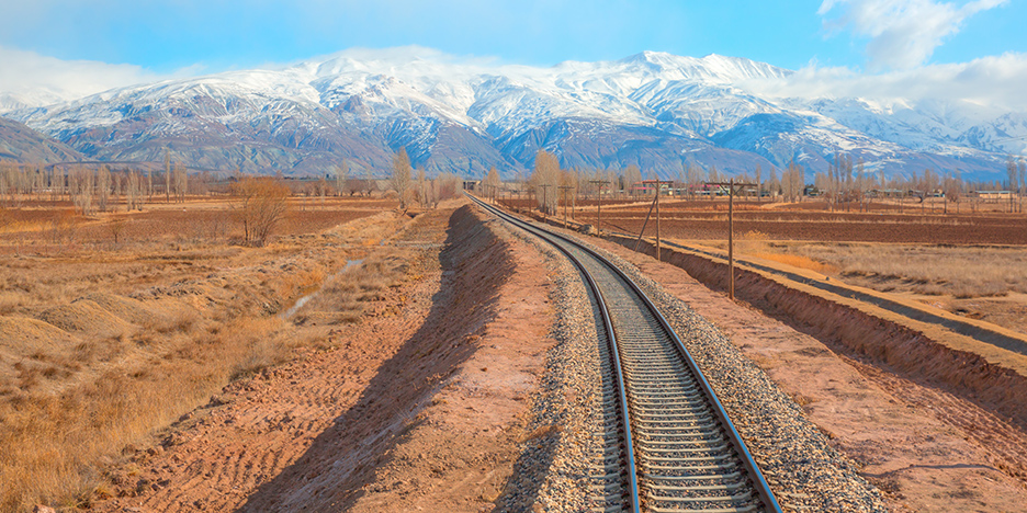Railroad track in the high desert receding towards snow-capped mountains