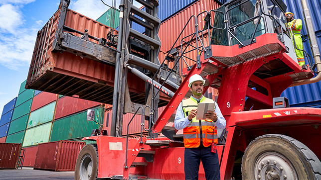 A man standing beside a forklift, ready to operate it and handle heavy loads efficiently.