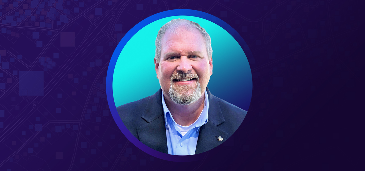 Jason Hall smiling in business attire overlaid on a turquoise and blue graphic background