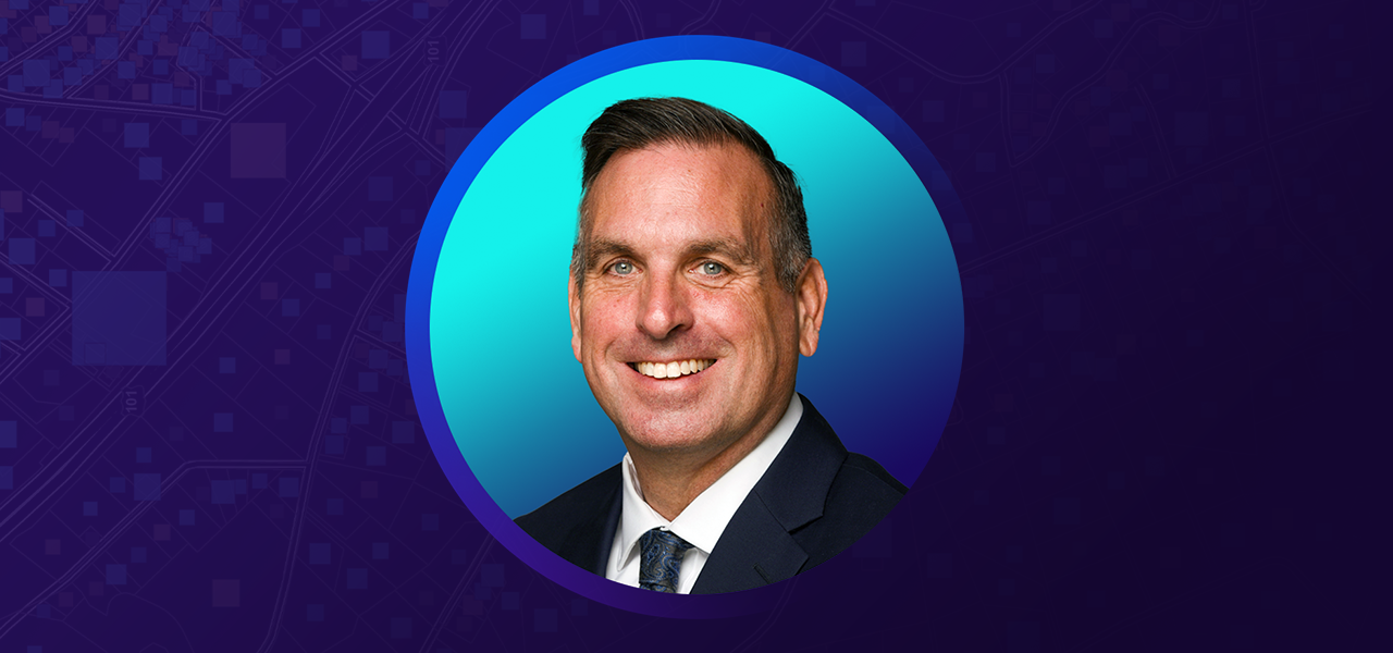John Nolte smiling and wearing a suit and tie overlaid on a blue and purple graphic background