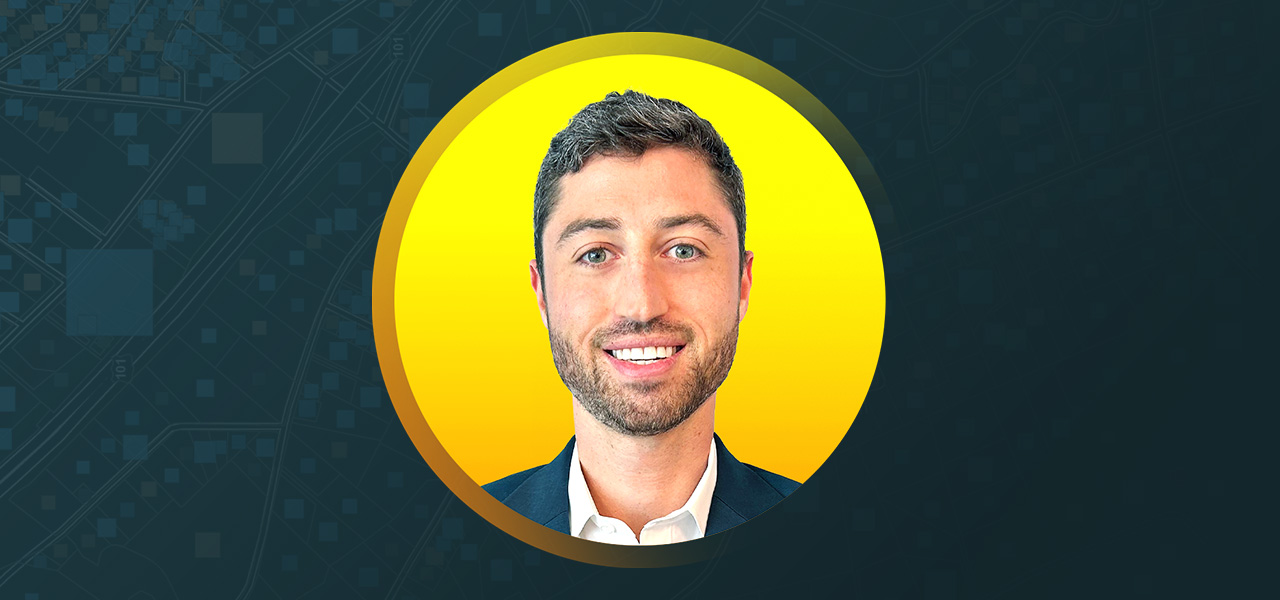Bruce Battle smiling in front of a yellow and teal background