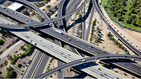 An aerial view of a complex layered freeway interchange with light traffic in every direction