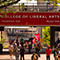 Students and staff walking outside on a sunny day on a college campus 