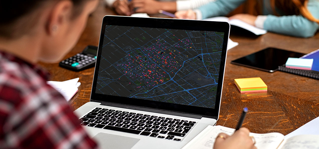 Foto di uno studente seduto in un'aula che esamina la mappa di concentrazione di una città sullo schermo di un PC portatile