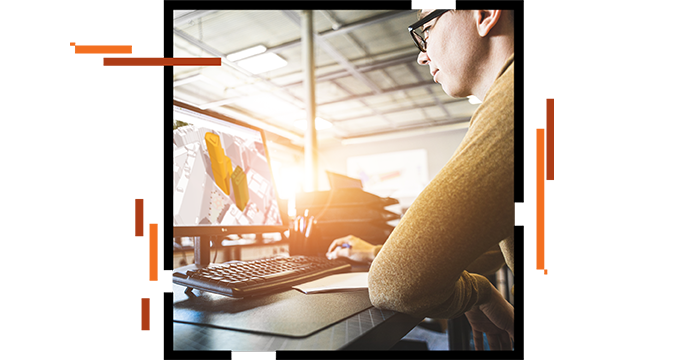 Person sitting at a desk and looking at a computer screen with a 3D image of buildings