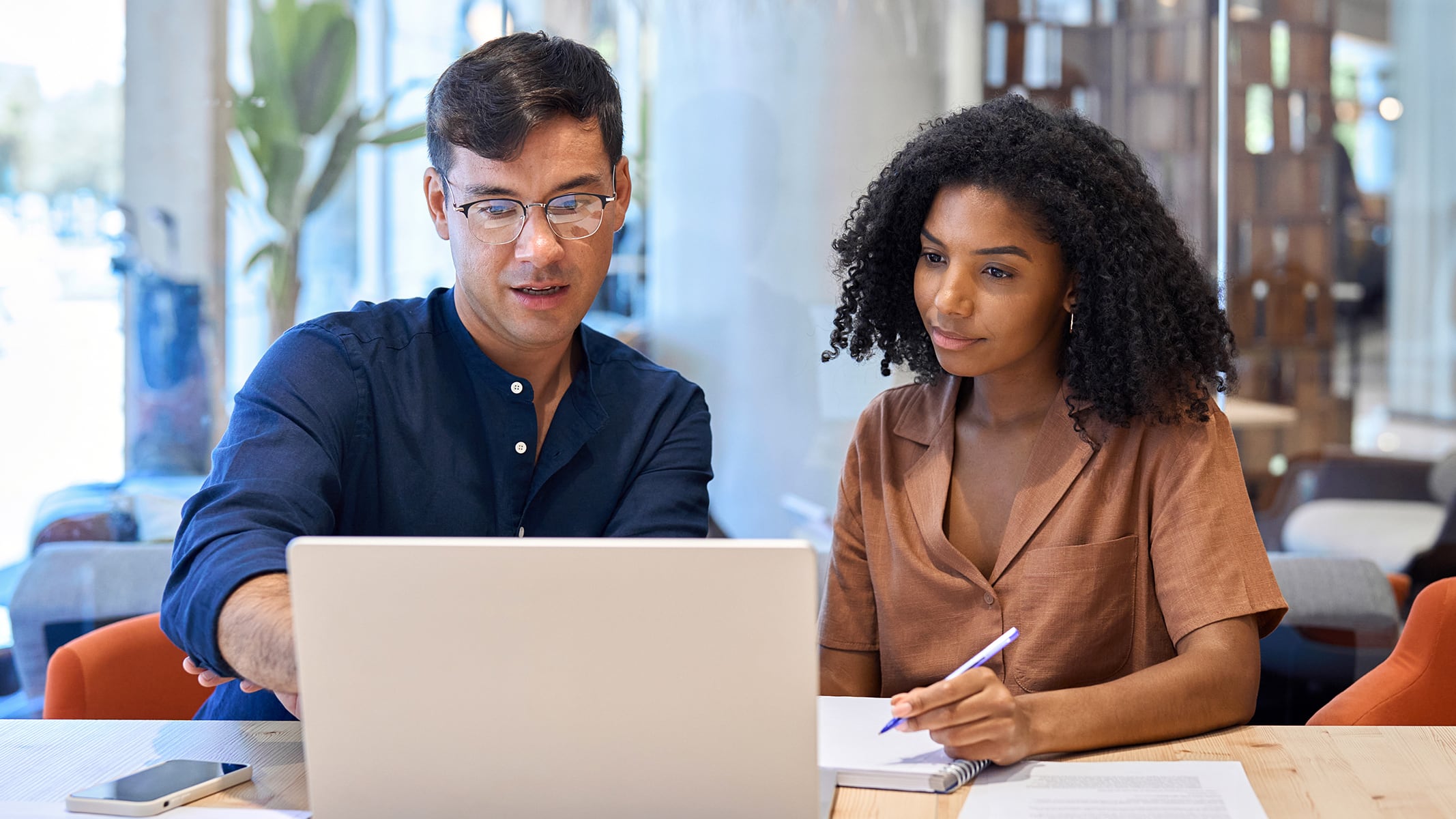 Two people sitting in front of a laptop and talking in a modern office