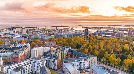 Aerial view of a tree-filled city beneath an orange and pink sunrise sky