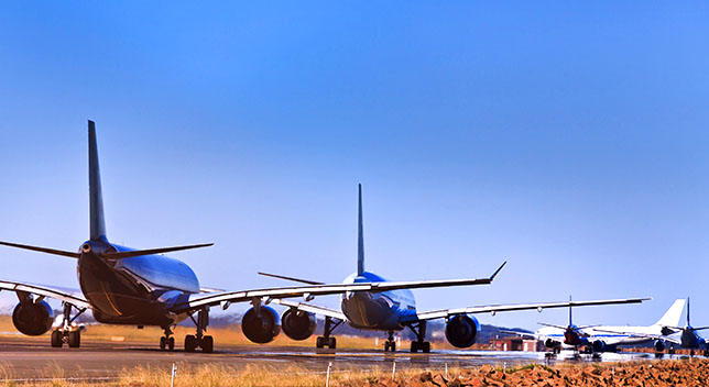 A photo of four airplanes parked on a runway in a yellow and brown field beneath a bright blue sky
