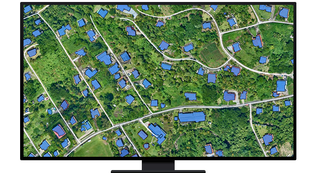 A graphic of a computer monitor displaying an aerial view of a green tree-filled suburb with houses shaded in blue