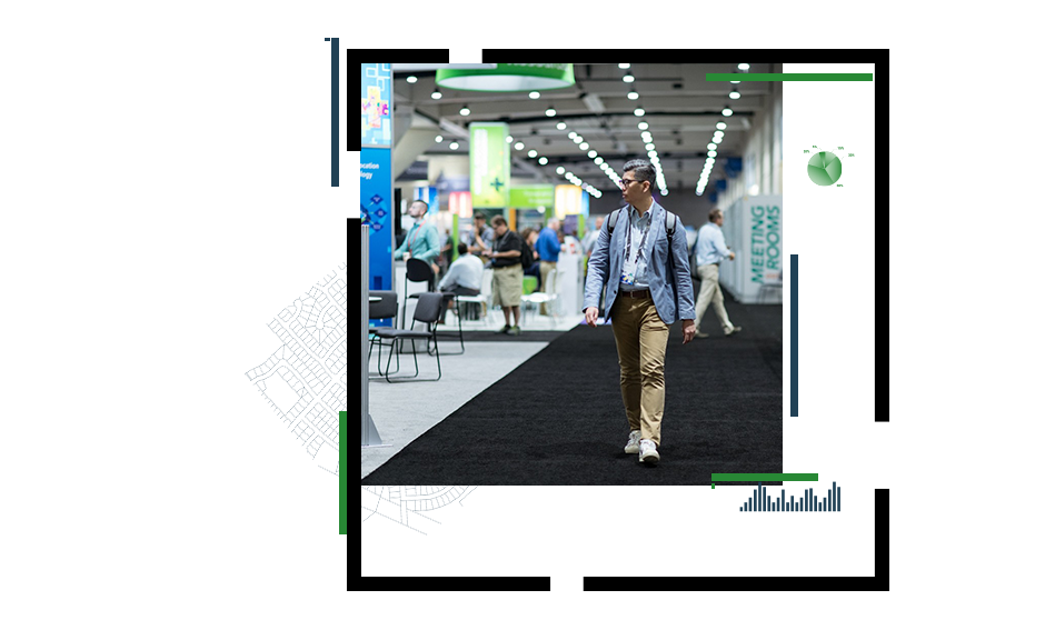 A conference attendee wearing khaki pants and a blue blazer walking through the Expo Hall at the Esri User Conference, and a woman in glasses looking at an ID card