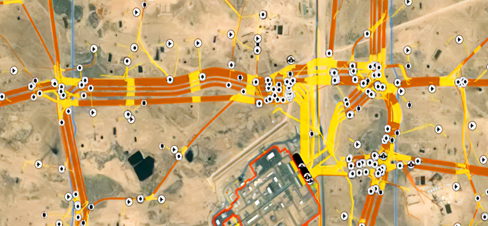 Aerial photo of a light brown desert area overlaid with road routes in orange and yellow scattered with white map points