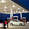 A clean red and white gas station brightly lit beneath a dark violet sunset sky