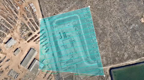 An aerial photo of an industrial site in a brown desert area overlaid with a large blue tinted square