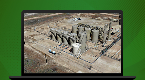 A graphic of a laptop displaying an aerial photo of a gray petroleum refinery