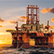 An orange oil rig at sea surrounded by choppy steel-blue waters beneath a deep orange sunset sky