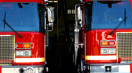 A closeup photo of two red fire trucks parked side by side