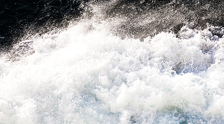A closeup photo of churning water and white spray from a stretch of river rapids
