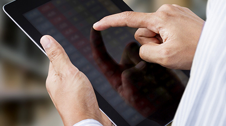 A closeup photo of a pair of hands holding and tapping a tablet