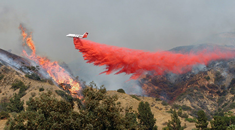 Plane dropping fire retardant over fire
