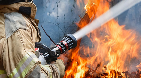 Firefighter spraying a fire with water from a firehose