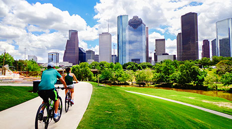 Two people riding bikes on a path with a city in the background