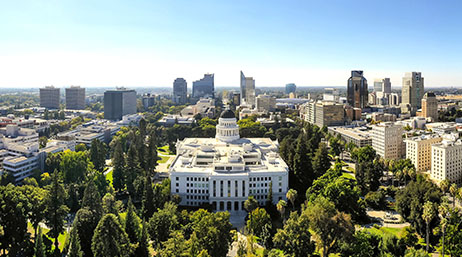 The California State Capitol building in Sacramento with trees and buildings surrounding it