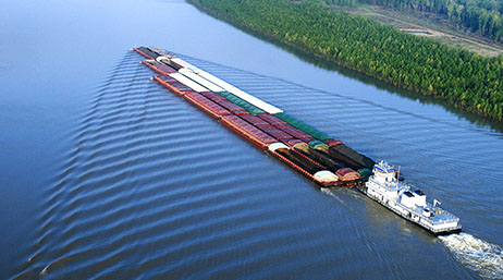 A cargo ship moving down a river with a forest on the side
