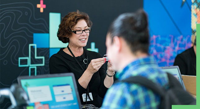 An employee looking at an identification card with a person using a computer in front of them