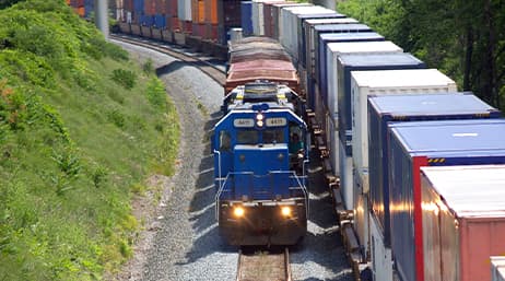 A freight train passing by the containers of another train headed in the opposite direction