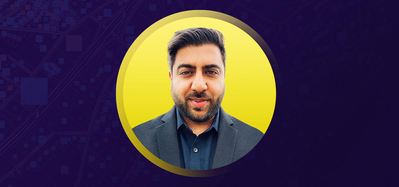 Rahul smiling in a business suit overlaid on a yellow and purple background 