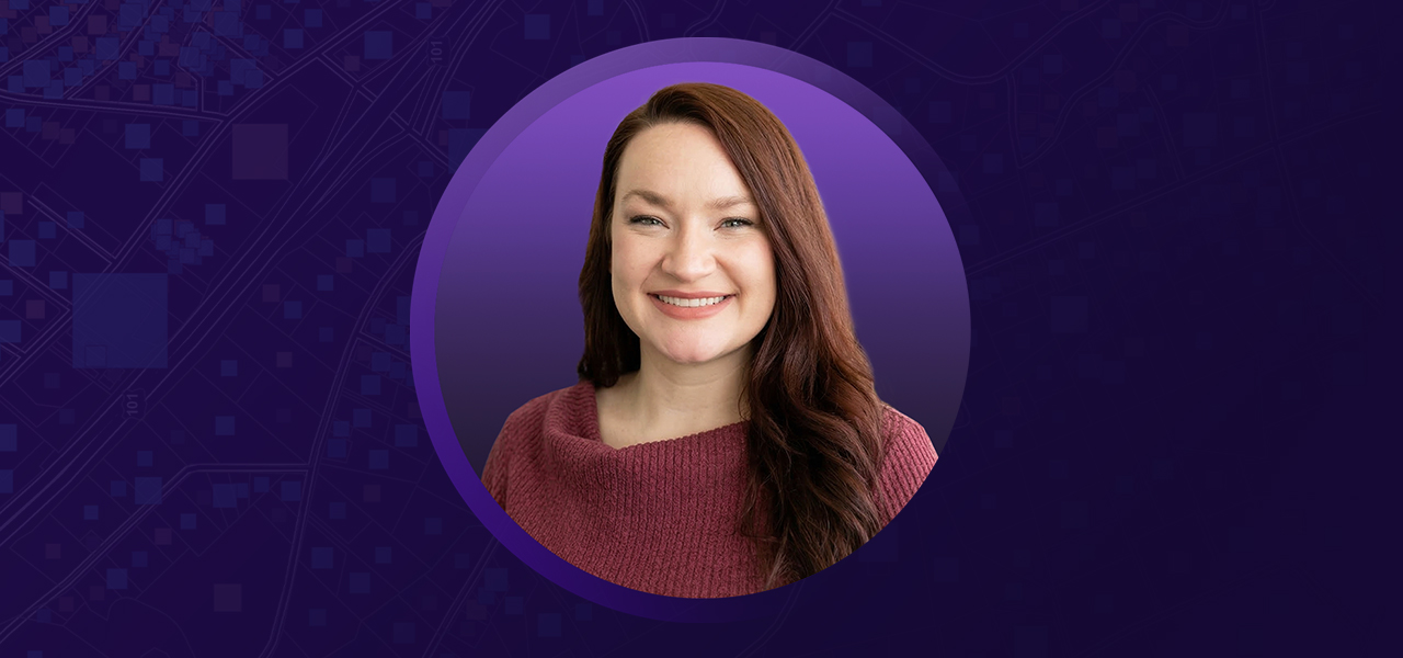 Portrait of Alyssa Wood smiling in a magenta sweater with a flat purple background