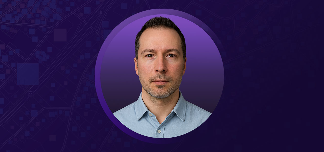 Joshua wearing a blue collared shirt overlaid on a purple background