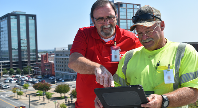 Two people looking at the same tablet computer outside