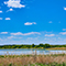 A large pond surrounded by new landscaping beside a district office under a pale clear sky