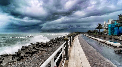 A photo of a boardwalk alongside a stormy beach under a sky heavy with dark clouds