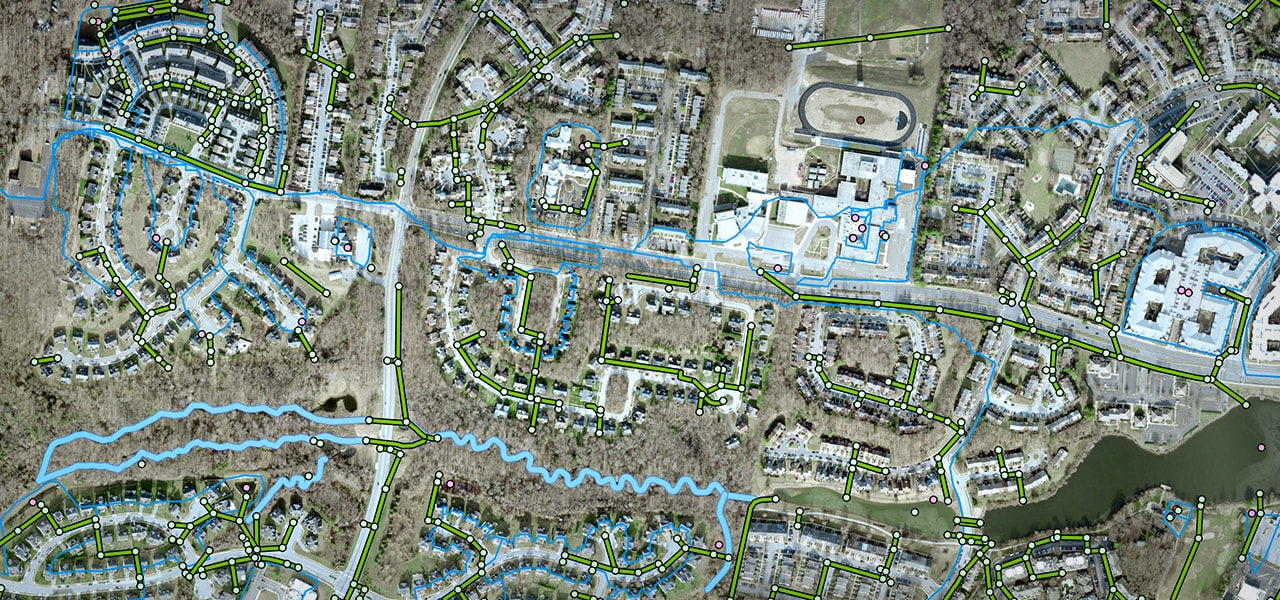 An aerial photo of a city near a river with routes shown in green and blue