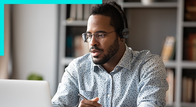 A photo of a professionally dressed person wearing a headset and using a laptop in a home office environment