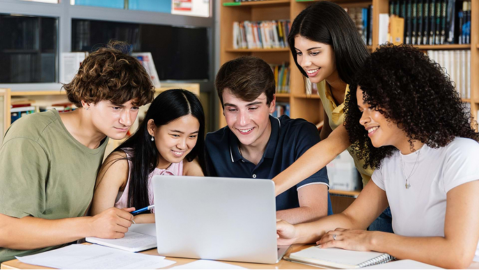 Students gathered around a laptop at a desk