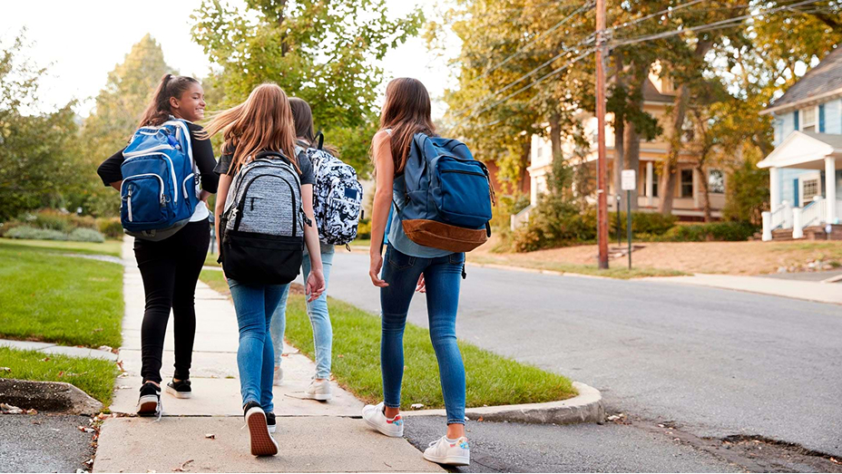 A group of students wearing backpacks and walking together in a residential neighborhood