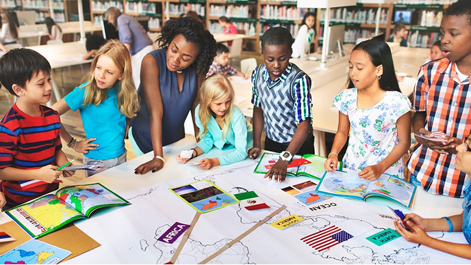 Young students standing around a classroom activity table with a teacher