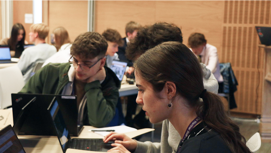 Studenti seduti a un tavolo che lavorano insieme sui propri laptop