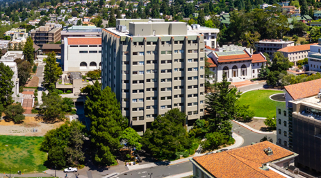 緑の芝生と背の高い緑の樹木を背景とした、白い建物がある伝統的なカレッジ キャンパスの航空写真