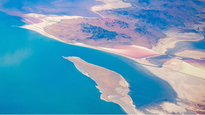 Aerial view of a pink and beige coastline beside aqua blue waters