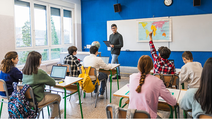 A sunlit modern classroom with young students using laptops at their desks