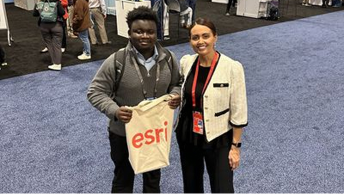 Pracownik firmy Esri i uczeń trzymający torbę z logo Esri podczas wydarzenia