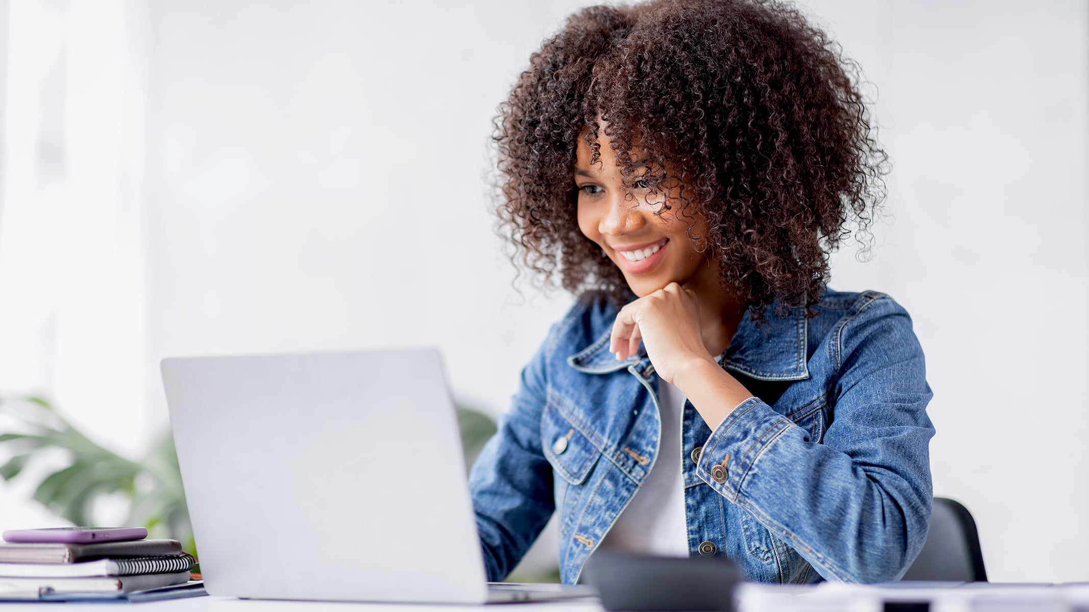 Un insegnante che indossa una giacca di jeans sorridente davanti a un laptop aperto