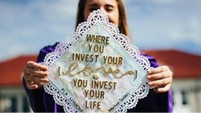 Absolwent trzymający czapkę z napisem: "Gdy inwestujesz w swoją miłość, inwestujesz w swoje życie"